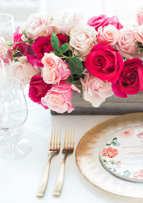 Pink flowers and floral plates on white table linens with gold accents